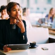 pensive black businesswoman using tablet computer in coffee shop
