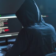 cybercrime, hacking and technology concept - male hacker in dark room writing code or using computer virus program for cyber attack