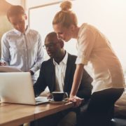 Group of entrepreneurs working using a laptop and holding a document