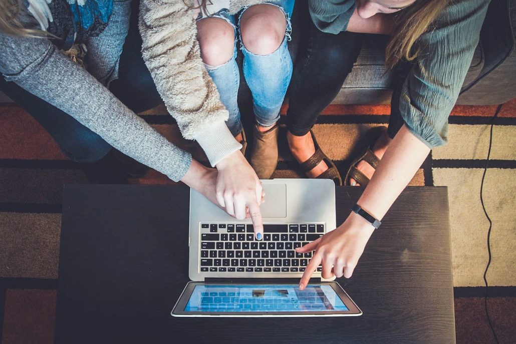 Group of young people working on laptop together; work tech publications concept