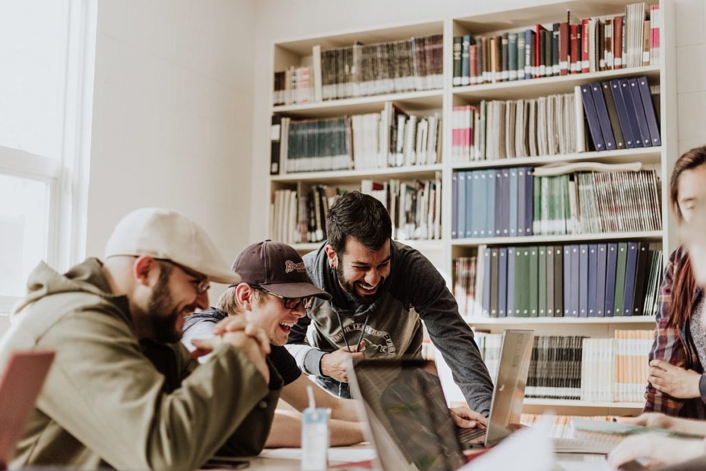 three young professions work around a single laptop; marketing work tech culture concept